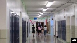 In this July 10, 2018 photo, students walk down a hallway at Lockport High School in Lockport, N.Y. On the upper left a camera with facial recognition capabilities hangs on the wall waiting for its installation to be completed. (AP Photo/Carolyn Thompson)