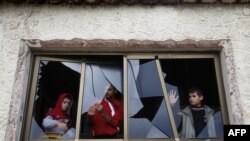 Palestinian boys pull shards of glass from a broken window at their home near the site of Israeli overnight attacks in Gaza City, Dec. 8, 2019.