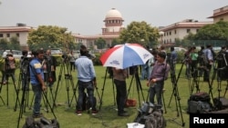 Television journalists are seen outside the Supreme Court building in New Delhi, India, August 22, 2017.