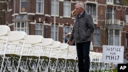 FILE - Relatives walk along 298 empty chairs, each chair for one of the 298 victims of the downed Malaysia Air flight MH17, are placed in a park opposite the Russian embassy in The Hague, Netherlands, on March 8, 2020.