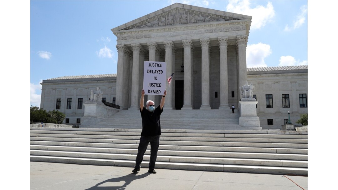 FILE - Demonstrator Bill Christeson holds a sign outside the U.S. Supreme Court, where justices ruled that a prosecutor in New York City can obtain President Donald Trump's financial records, including tax returns, in Washington, July 9, 2020.