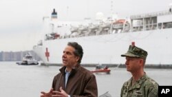 New York Go. Andrew Cuomo, left, speaks as he stands beside Rear Adm. John B. Mustin after the arrival of the USNS Comfort, a naval hospital ship with a 1,000 bed-capacity, March 30, 2020, at Pier 90 in New York.