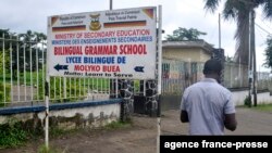 FILE - A man walks past the entrance of the bilingual Lycee of Buea, capital of south west Cameroon, one of the two regions of the country in the grip of a violent crisis, Sept. 24, 2019.