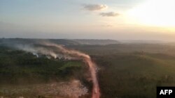 In this aerial view the red dust of the BR230 highway, known as "Transamazonica," mixes with fires at sunset in the agriculture town of Ruropolis, Para state, northern Brazil, Sept. 6, 2019.