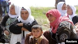 More than 200 Yazidi sect members, freed eight months after they were taken captive by Islamic State militants, wait on the edge of Kirkuk for relocation, April 8, 2015.