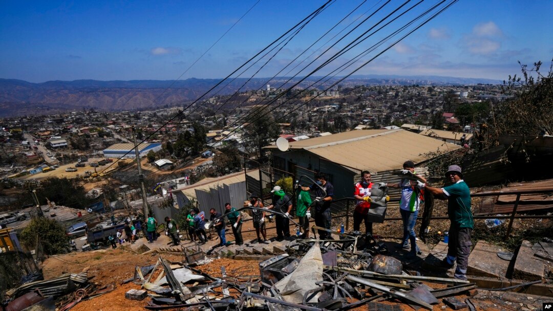 Aficionados del club de fútbol Wanders hacen labores voluntarias de limpieza en un área afectada por incendios forestales en el vecindario Villa Independencia, el martes 6 de febrero de 2024, en Viña del Mar, Chile.