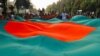 Orang-orang mengibarkan bendera besar Bangladesh, tiga hari menjelang peringatan 50 tahun Hari Kemenangan negara itu, di depan gedung parlemen di Dhaka, Bangladesh, 13 Desember 2021. (Foto: REUTERS/Mohammad Ponir Hossain...