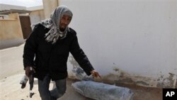 Anti-Gadhafi rebel in front of an unexploded bomb from an air strike by Gadhafi's warplanes, in the town of Ras Lanouf, eastern Libya, March 8, 2011