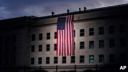 Bendera Amerika berukuran raksasa dikibarkan di Pentagon menjelang upacara di National 9/11 Pentagon Memorial untuk menghormati 184 orang yang tewas dalam serangan teroris 2001 di Pentagon, Washington, Jumat 11 September 2020. (AP Photo / J . Scott Applewhite)