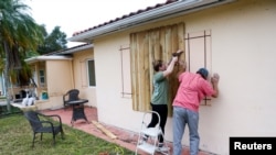 Yadda mutane ke kafe tagogi da kafofin gidajensu a wani mataki na tare karfin guguwar a jihar Florida