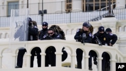 Police keep a watch on demonstrators trying to break through a police barrier, Jan. 6, 2021, at the Capitol in Washington.