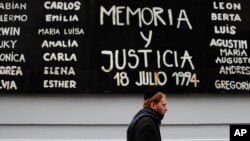 FILE — A man walks past a board that says in Spanish: "Memory and Justice," amid the names of people who died in the bombing of the AMIA Jewish center in Buenos Aires, July 18, 2019.