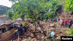 FILE - Rescuers search for bodies and survivors after a dam collapsed causing flooding, destroying homes and killing dozens in Mbankolo, Yaounde, Cameroon, October 9, 2023.