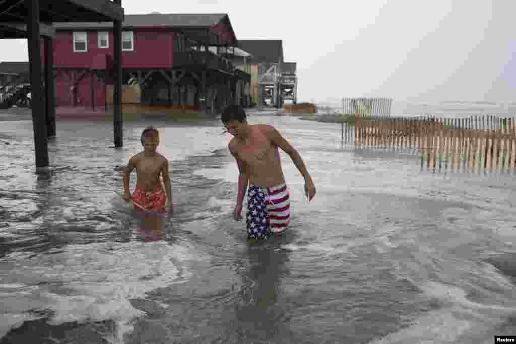 Kyler Cook, 18, (R) and Brodie Fox, 10, both from Tiffen, Ohio, walk through the storm surge of Hurricane Arthur, in Ocean Isle Beach, North Carolina, July 3, 2014