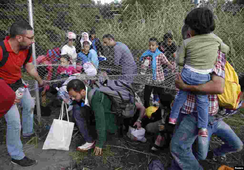 Migrants pass under highway security fence as they try to find a new way to enter Hungary after Hungarian police sealed the border with Serbia near the village of Horgos, Serbia, Sept. 14, 2015, near the Hungarian migrant collection point in Roszke.