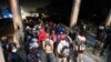 Hondureños que participan en una nueva caravana de migrantes, que se dirigirá a Estados Unidos, pasan por un puesto de control policial después de mostrar sus identificaciones a los oficiales de policía, en San Pedro Sula, Honduras, 14 de enero de 2021.