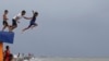 Boys jump into the water despite strong waves after a strong downpour at Manila&#39;s bay, Philippines.