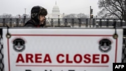 Un partidario del presidente electo de Estados Unidos, Donald Trump, pasa junto a una barrera de seguridad cerca del Capitolio de Estados Unidos en Washington, D.C., el 19 de enero de 2025, un día antes de la investidura de Trump. (Foto de ANDREW CABALLERO-REYNOLDS / AFP)