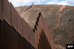 Construction crews work on a new section of the US-Mexico border fencing at El Nido de las Aguilas, eastern Tijuana, Baja California state, Mexico on Jan. 20, 2021.