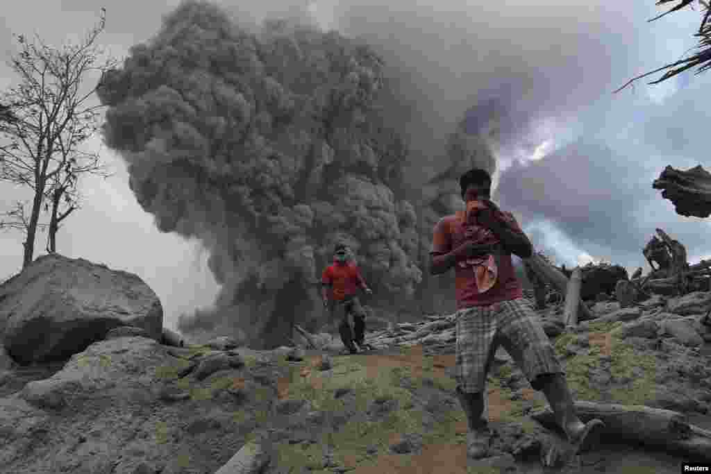 Villagers run on ash during the eruption of Mount Sinabung volcano near Gamber village in Karo district, in Indonesia&#39;s North Sumatra province.