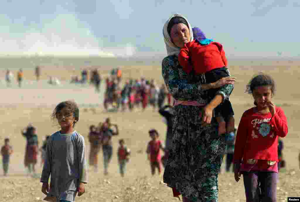 Para pengungsi dari sekte minoritas Yazidi melarikan diri dari kekerasan pasukan ISIS di kota Sinjar, Irak, berjalan menuju perbatasan Suriah di pinggiran gunung Sinjar, Agustus 2014. (Reuters/Rodi Said)