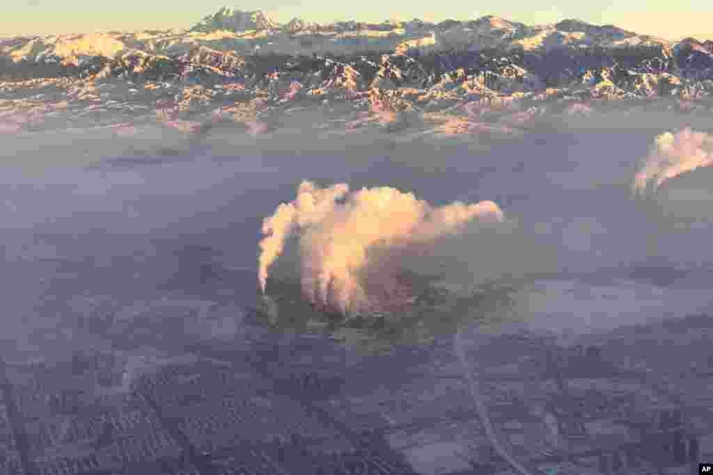 FILE - In this photo taken from a plane, smoke stacks are seen near the city of Urumqi China's northwestern region of Xinjiang, Dec. 5, 2018.