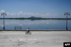 A boy rides a bicycle along the bank of the Dal Lake during a government-imposed nationwide lockdown as a preventive measure against the COVID-19 coronavirus, in Srinagar on April 23, 2020.