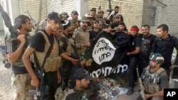 FILE - Iraqi security forces backed by Shiite and Sunni pro-government fighters celebrate as they hold a flag of the Islamic State militant group they captured in Ramadi, Anbar province, Iraq, July 26, 2015.