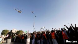 FILE - A military helicopter hovers above as followers of the Houthi movement as they demonstrate to show support to the movement in Sanaa, January 23, 2015.