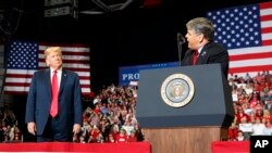 President Donald Trump listens Fox News' Sean Hannity speak during a rally at Show Me Center in Cape Girardeau, Mo., Nov. 5, 2018.