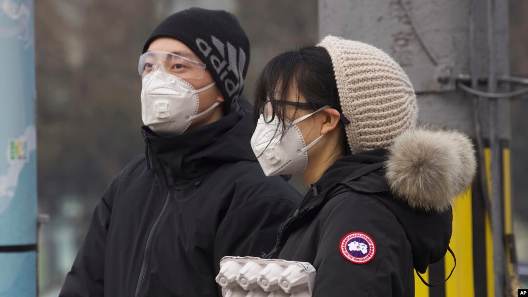 Residents wearing masks wait at a traffic light in Beijing, China Thursday, Feb. 13, 2020.