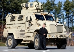 In this Nov. 13, 2013 photo, Warren County Undersheriff Shawn Lamouree poses in front the department's mine resistant ambush protected vehicle, or MRAP, in Queensbury, N.Y.