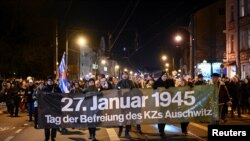 FILE - People walk with a banner reading "27th January 1945, day of the liberation of the Auschwitz concentration camp" during a chain of lights on the International Holocaust Remembrance Day, in district Pankow, Berlin, Germany January 27, 2024.