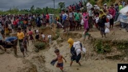 Rohingya Muslims, who crossed over from Myanmar into Bangladesh, walk through a muddy field after collecting aid from a distribution center near Balukhali refugee camp, Bangladesh, Thursday, Sept. 28, 2017. 