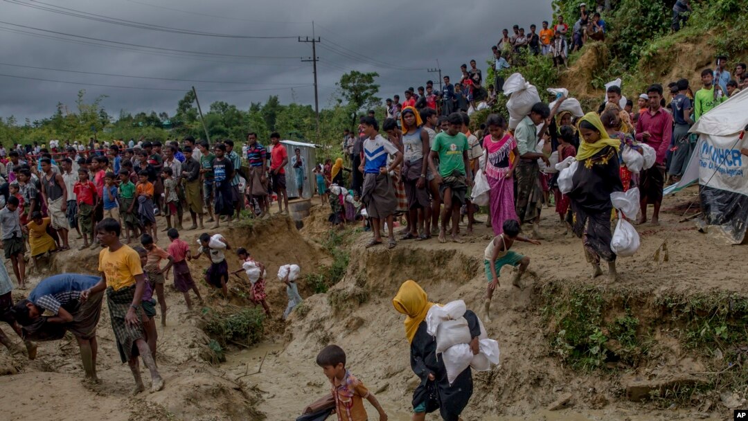 Muslim Rohingya, yang menyeberang dari Myanmar ke Bangladesh, melewati lapangan berlumpur setelah menerima bantuan dari pusat distribusi bantuan dekat kamp pengungsi Balukhali, Bangladesh, Kamis, 28 September 2017. 