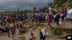 Muslim Rohingya, yang menyeberang dari Myanmar ke Bangladesh, melewati lapangan berlumpur setelah menerima bantuan dari pusat distribusi bantuan dekat kamp pengungsi Balukhali, Bangladesh, Kamis, 28 September 2017. 