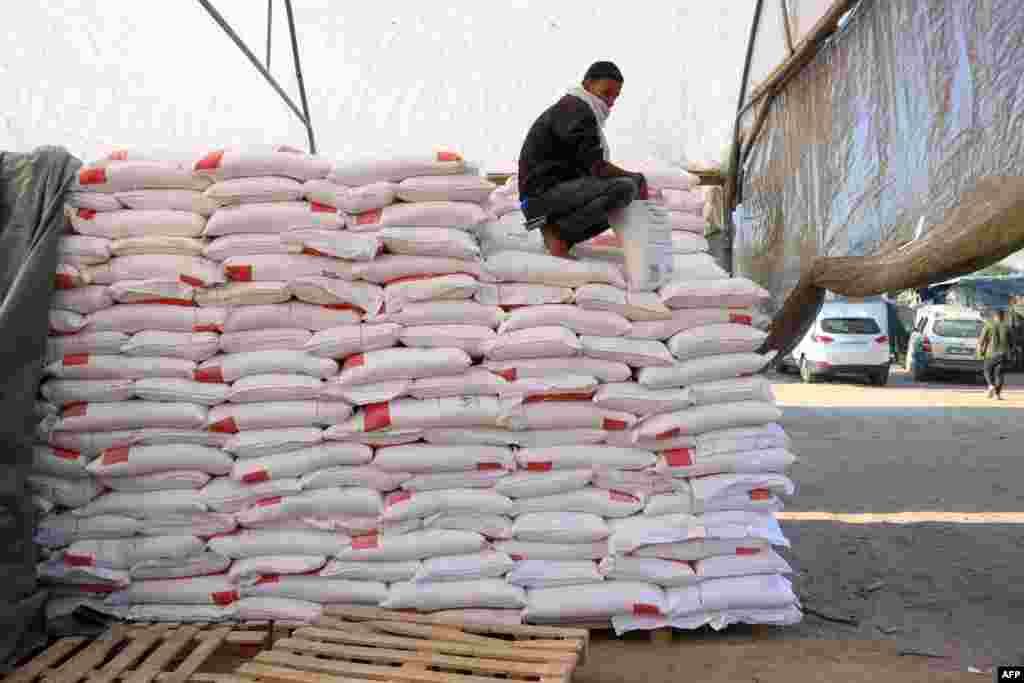 A Palestinian worker rests on a stack of flour at an aid distribution center in the southern Gaza Strip city of Khan Yunis, amid the ongoing war between Israel and the Palestinian Hamas movement.