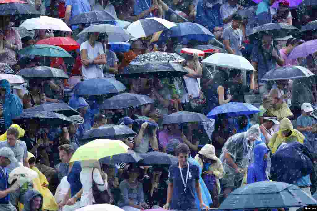 Para penonton menunggu di bawah payung mereka, sementara hujan menghentikan pertandingan kejuaraan tennis AS Terbuka di New York.