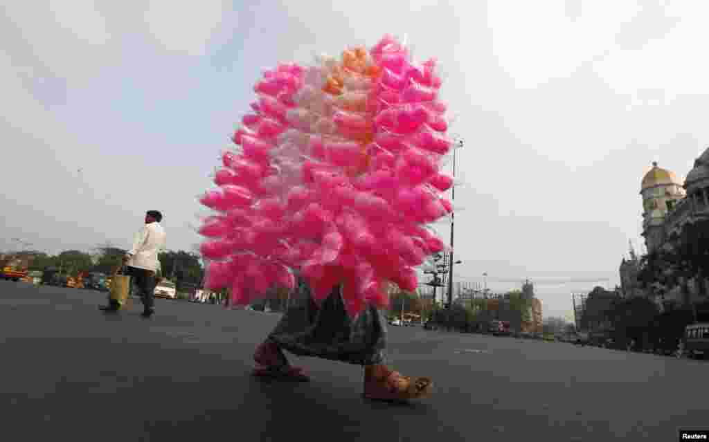 A vendor selling cotton candy crosses a road in Kolkata, India. 