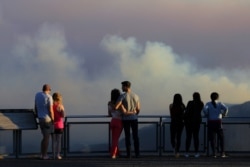 People watch as smoke from the Green Wattle Creek fire is seen from Echo Point lookout in Katoomba, as bushfires continue to blaze in New South Wales, Australia, Dec. 6, 2019.