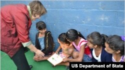 U.S. Ambassador Lisa Kubiske hands a book to girls at the Nueva Suyapa Outreach Center in Tegucigalpa, Honduras. 