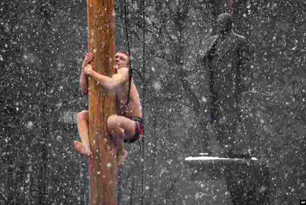 A man climbs on a pole in snowfall to get a prize during celebrations of Maslenitsa, or Pancake Week, in Veliky Novgorod, some 550 kilometers (340 miles) northeast of Moscow, Russia.
