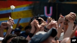 People raise their hands in protest and remembrance during the one year anniversary of the 7.1 earthquake, at the Multifamiliar de Tlalpan, in Mexico City, Sept. 19, 2018. 