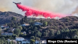 Sebuah tanker udara menjatuhkan bahan kimia anti api di Palisades Fire, salah satu kebakaran beruntun yang melanda Los Angeles County, seperti terlihat dari Woodland Hills, kawasan Los Angeles, California, AS, 11 Januari 2025. (Foto: Ringo Chiu/Reuters)