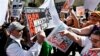 An anti-immigration rights protester, left, holds up a sign as he is pointed at and shouted at by immigration rights marchers during a Puente Movement event March Against Deportation, Family Separation, and Workplace Raids on March 11, 2013, in Phoenix.