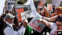 An anti-immigration rights protester, left, holds up a sign as he is pointed at and shouted at by immigration rights marchers during a Puente Movement event March Against Deportation, Family Separation, and Workplace Raids on March 11, 2013, in Phoenix.