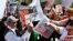 An anti-immigration rights protester, left, holds up a sign as he is pointed at and shouted at by immigration rights marchers during a Puente Movement event March Against Deportation, Family Separation, and Workplace Raids on March 11, 2013, in Phoenix.