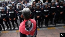 A Thai pro-democracy protester wears scarf with a portrait of former Prime Minister Yingluck Shinawatra during a gathering to mark the fourth anniversary of the military take-over of government in Bangkok, Thailand, Tuesday, May 22, 2018. (AP Photo/Sakcha