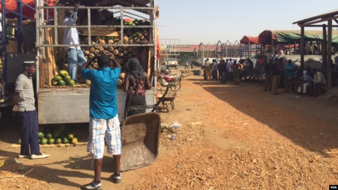 Workers offload fruit trucks from Uganda at Juba's Gumbo Market on March 10, 2015. Business owners are feeling the pressure as the strength of the South Sudanese pound weakens. (Photo: G. Joselow / VOA)
