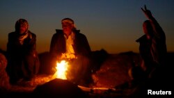 Turkish Kurds warm themselves around an open fire as they watch the Syrian town of Kobani, near the Mursitpinar border crossing, on the Turkish-Syrian border in the southeastern town of Suruc, Turkey, Oct. 21, 2014.